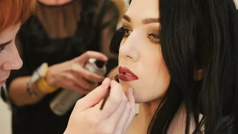 Make-up artist makes make-up young woman lips with lip pencil to stroke the lips Video stock 73826978