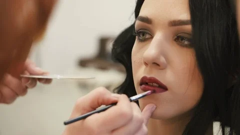 Make-up artist makes make-up young woman lips with lip pencil to stroke the lips Stock Footage 73827882