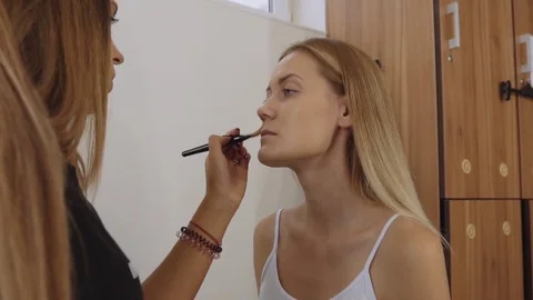 Make-up artist makes up a young beautiful woman with a brush. Apply tonal cream Stock Footage 81045622