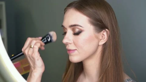 Make-up artist making face correction by brush. Shining eyes, glitters Stockbeeldmateriaal 154964538