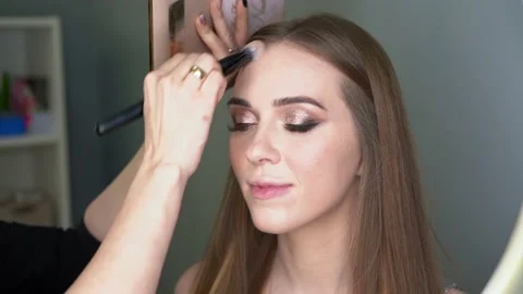 Make-up artist making face correction by brush. Shining eyes, glitters Stock Footage 154964616
