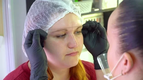 Make-up artist marks up client eyebrows in front of permanent makeup Stock Footage 146808239