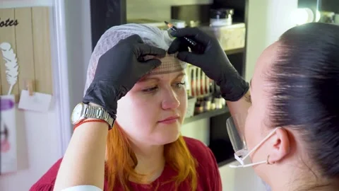 Make-up artist marks up client eyebrows in front of permanent makeup Stock Footage 147351766