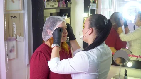 Make-up artist marks up client eyebrows in front of permanent makeup Stock Footage 148117951