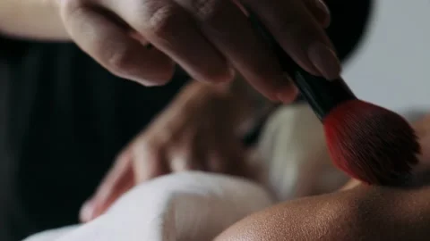 Make-up artist moves a brush along a girl's neckline Stock Footage 270963953