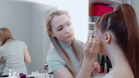 The make-up artist paints the eyebrow model and smiles. Video stock 149685033