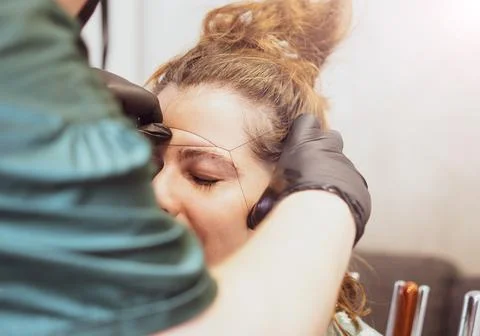 Make-up artist plucking eyebrows with a thread Professional face care. Stock Photos