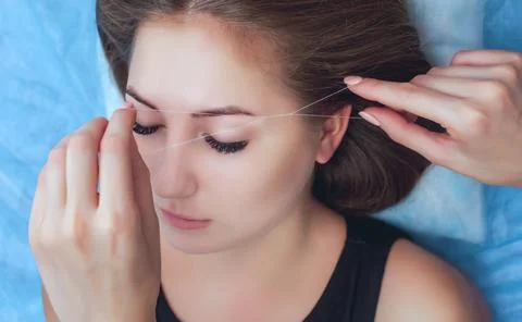 A make-up artist plucks an eyebrow with a thread Stock Photos