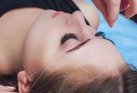 A make-up artist plucks an eyebrow with a thread Stock Photos