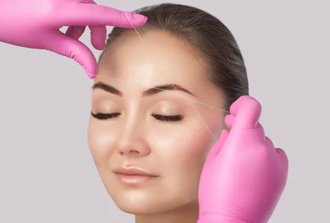 The make-up artist plucks eyebrows with a thread close-up. Face care, beauty  Stock Photos