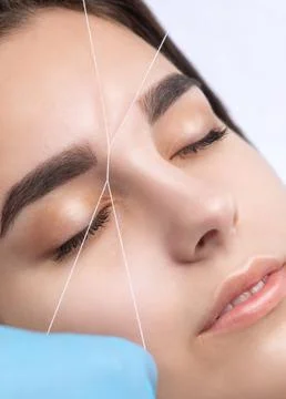The make-up artist plucks eyebrows with a thread close-up. Women's cosmetolog Stock Photos