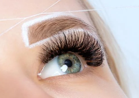 The make-up artist plucks eyebrows with a thread close-up. Woman Having Per.. Stock Photos