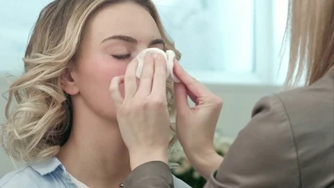Make-up artist preparing and cleaning skin of young blond model Video stock 74658382