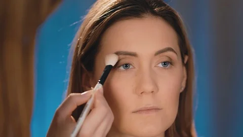 The make-up artist puts dark shadows on the eyelids, a professional white brush Stock-Footage 101147675
