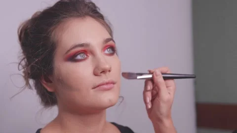 A make-up artist shades bronzer under a model's cheekbones Stock Footage 142201414