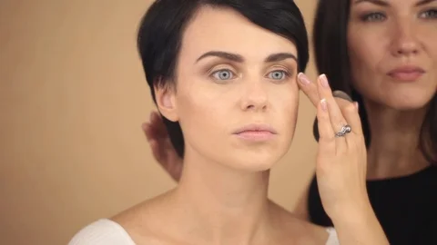 The make-up artist strikes the last strokes of a beautiful young model, close-up Stock Footage 86992054