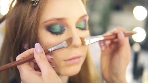 Make-up artist structuring nose of the young woman using foundation and two Stock Footage 88955851
