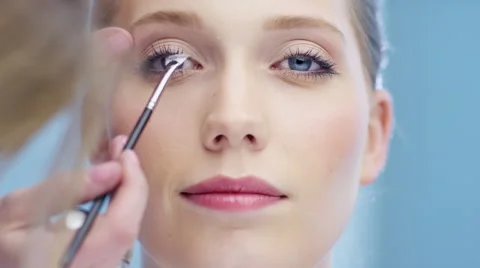Make-up artist is working on attractive young woman in studio Stock Footage 62243177