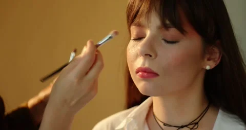 A make-up artist's hand applies a tone to the skin with a brush. Stock Footage 279916228