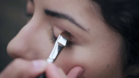 Make up artist's hand Applying eyeshadow to the eyes of a pretty woman Stock Footage 75097894