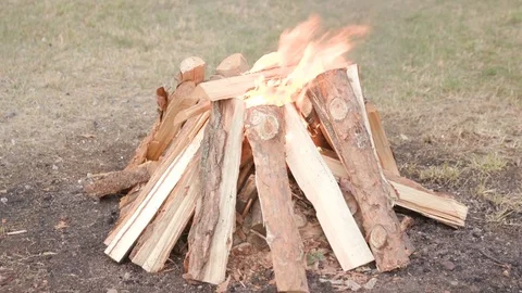 Make a big bonfire in the meadow. Beautiful bonfire made of wooden logs. Stock Footage 119882419