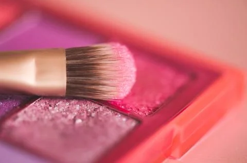 Make up brush on glitter pink shadows close up. Selective focus. Stock Photos