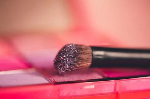 Make up brush with glitter shaows closeup. Selective focus. Stock Photos