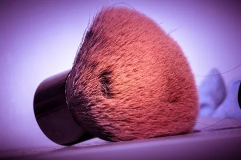 Make-up brush with pink powder explosion on a purple background Stock Photos