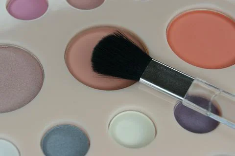 The make up brush is placed on the eye shadow palette. Close up. Stock Photos