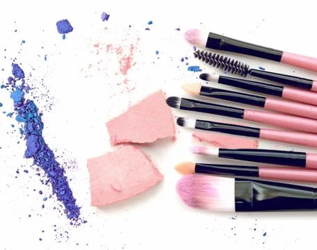 Make up brushes and crushed eyeshadow on white background Stock Photos