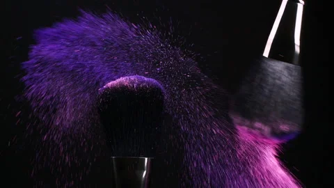 Make-up brushes with pink and purple flying eye shadow powder particles on black Stock Footage 172054274