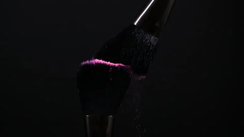 Make-up brushes with pink and purple flying eye shadow powder particles on black Stock Footage 173361517