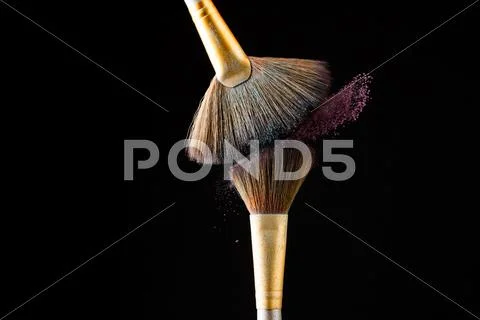 Make-up brushes with pink powder isolated on black background Stock Photos