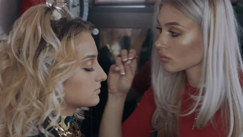 The make up concentrated artist puts false eyelashes with tweezers, young model Stock Footage 157556726