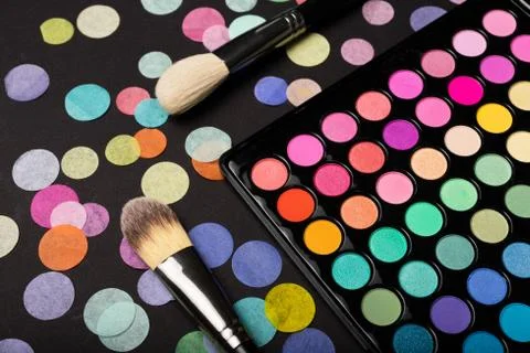 Make-up eyeshadow palette with brushes on back background with confetti Stock Photos