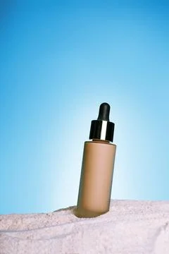 Make up foundation bottle with sunscreen on blue background and sand textur.. Stock Photos