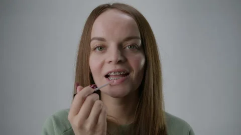 Make-up in front of the camera. A woman with braces. White studio background Stock Footage 267830065