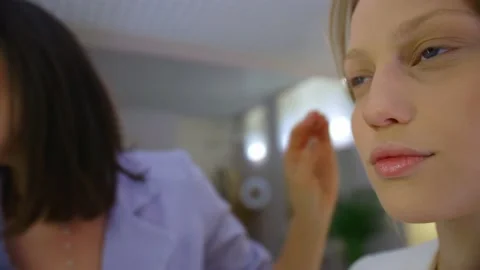 A make-up girl puts makeup on a blonde , two girls do makeup, a professional Stock-Footage 136507285