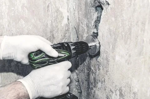 Make a hole in the wall for an electrical outlet. Master's hands with an elec Stock Photos