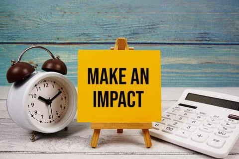 Make An Impact text written on paper card with calculator and alarm clock o.. Stock Photos