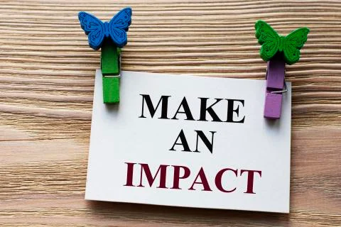 MAKE AN IMPACT - word on a white sheet with beautiful clothespins on a wooden Stock Photos