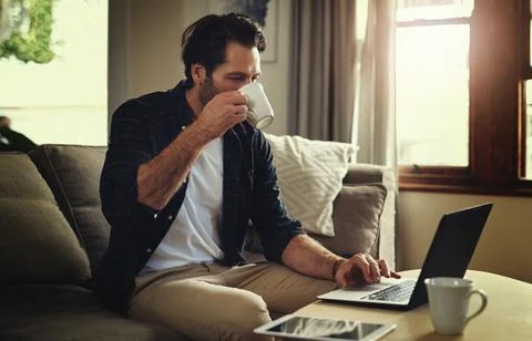 Make it easy to take it easy. a handsome young man using his laptop while Stock Photos