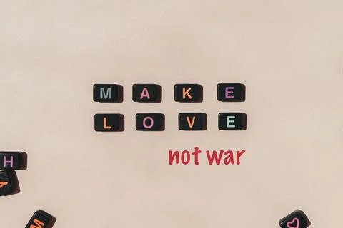 Make love not war. Black beads making phrase on beige background Stock Photos