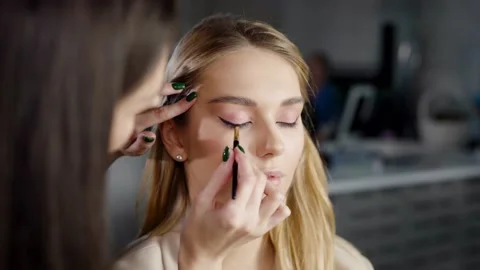 The make-up master makes a makeup of the model, draws arrows with a brush Stock Footage 236472703