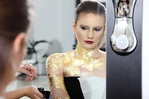 Make up model at mirror, gilded body paint Stock Photos
