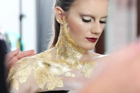 Make up  model at mirror, gilded body paint Stock Photos
