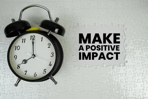 Make A Positive Impact text with alarm clock on white background Stock Photos