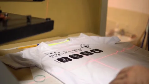 Make a print on t-shirts. The operator puts a t-shirt under the laser for Video stock 92498556
