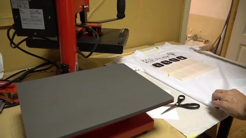 Make a print on t-shirts. The operator puts a t-shirt under the press, imposes a Stock Footage 92498612
