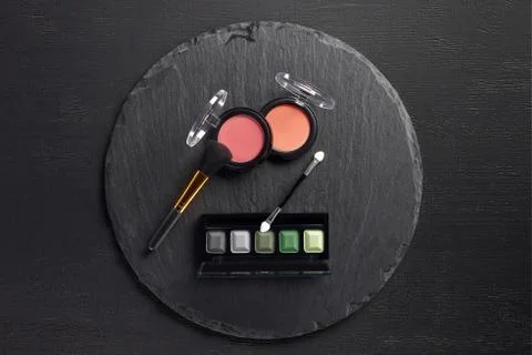 Make up set with brush, blush and eye shadows on round slate background Stock Photos